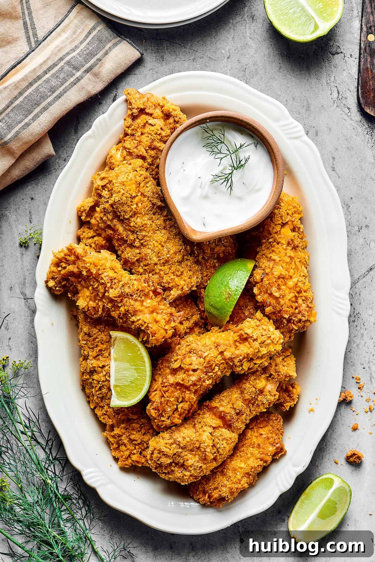 Air-fried chicken pieces on a platter garnished with lime wedges and a small dish of dipping sauce, ready for serving.