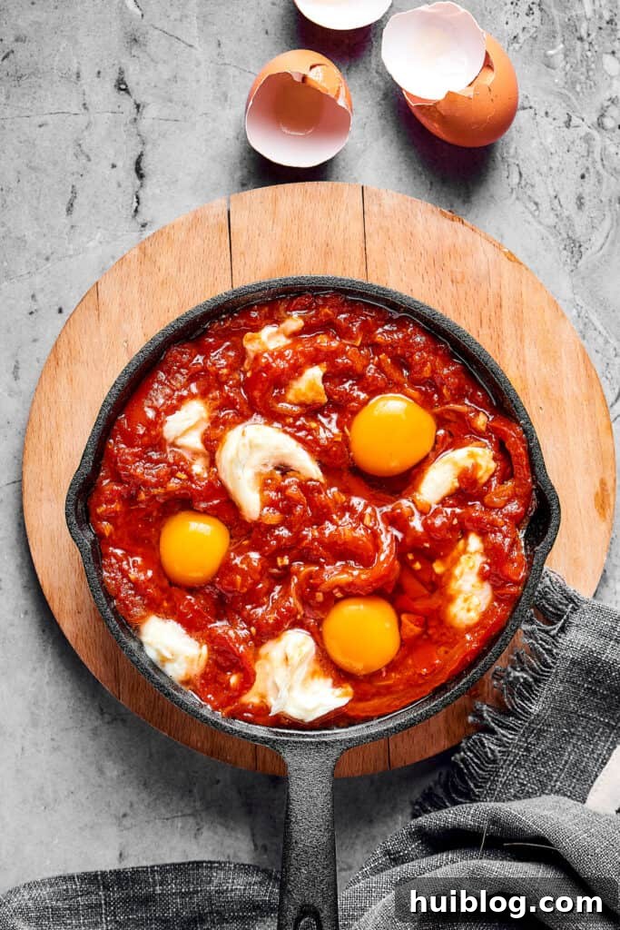 Eggs cracked into the shakshuka sauce.