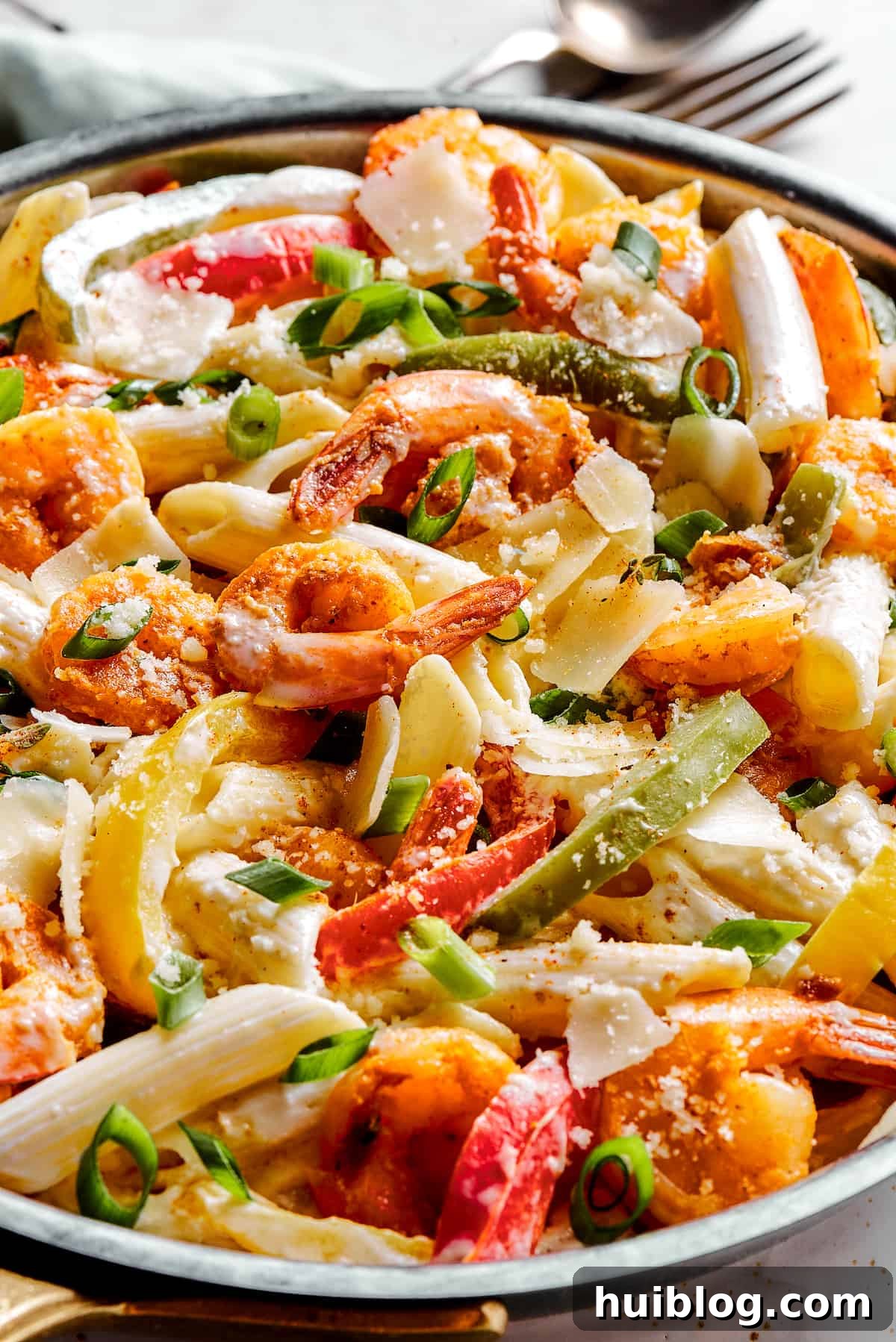 A skillet of bell peppers, pasta, and spicy shrimp swimming in a rich, creamy Rasta Pasta sauce.