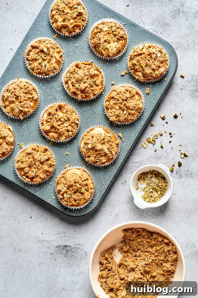 Swirled Pumpkin Cream Cheese Muffins 7 Muffins in a tin, generously topped with a crumbly streusel mixture, awaiting their time in the oven.