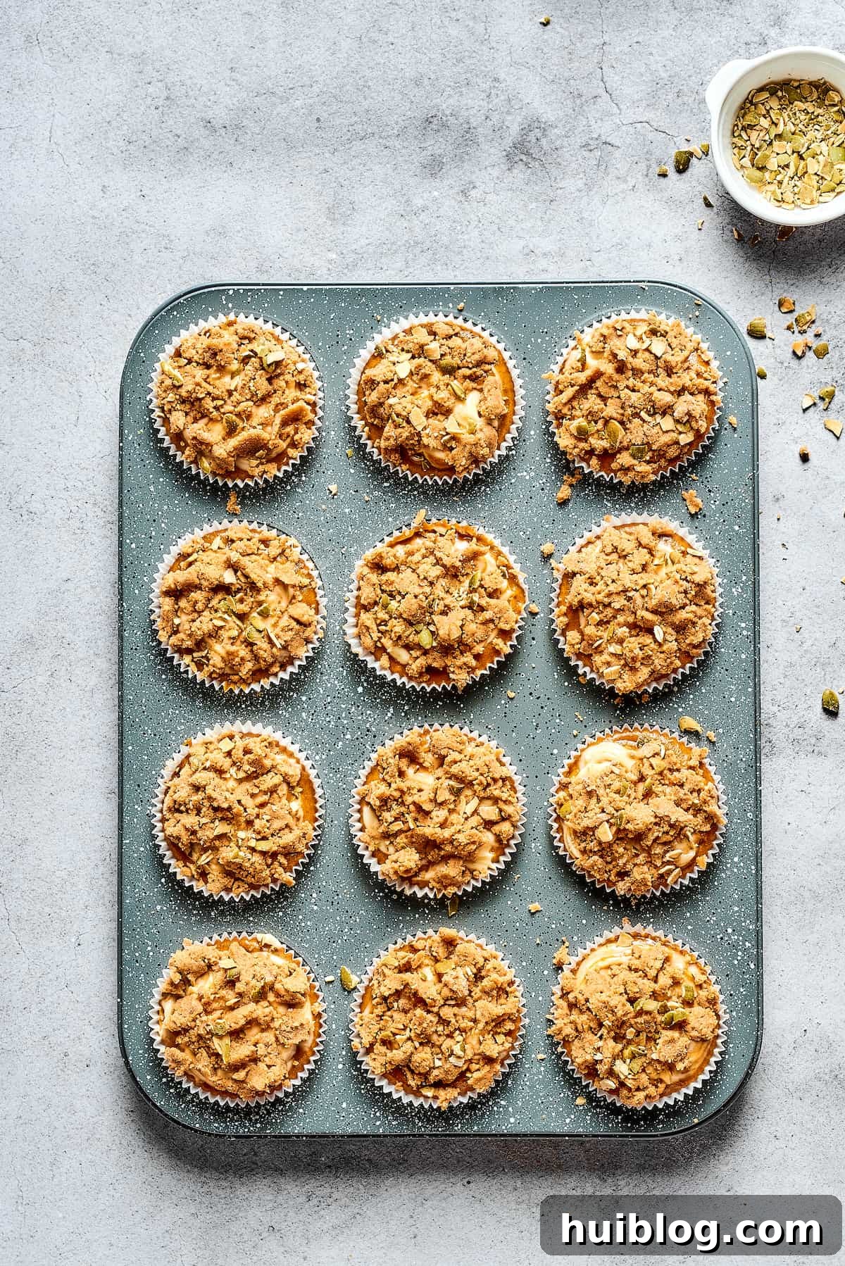 Pumpkin Cream Cheese Muffins are a heavenly mix of spiced pumpkin cake and smooth cream cheese swirl, with a buttery, streusel-like topping. Freshly baked pumpkin cream cheese muffins still nestled in their muffin tin, steam gently rising, highlighting their irresistible appeal.