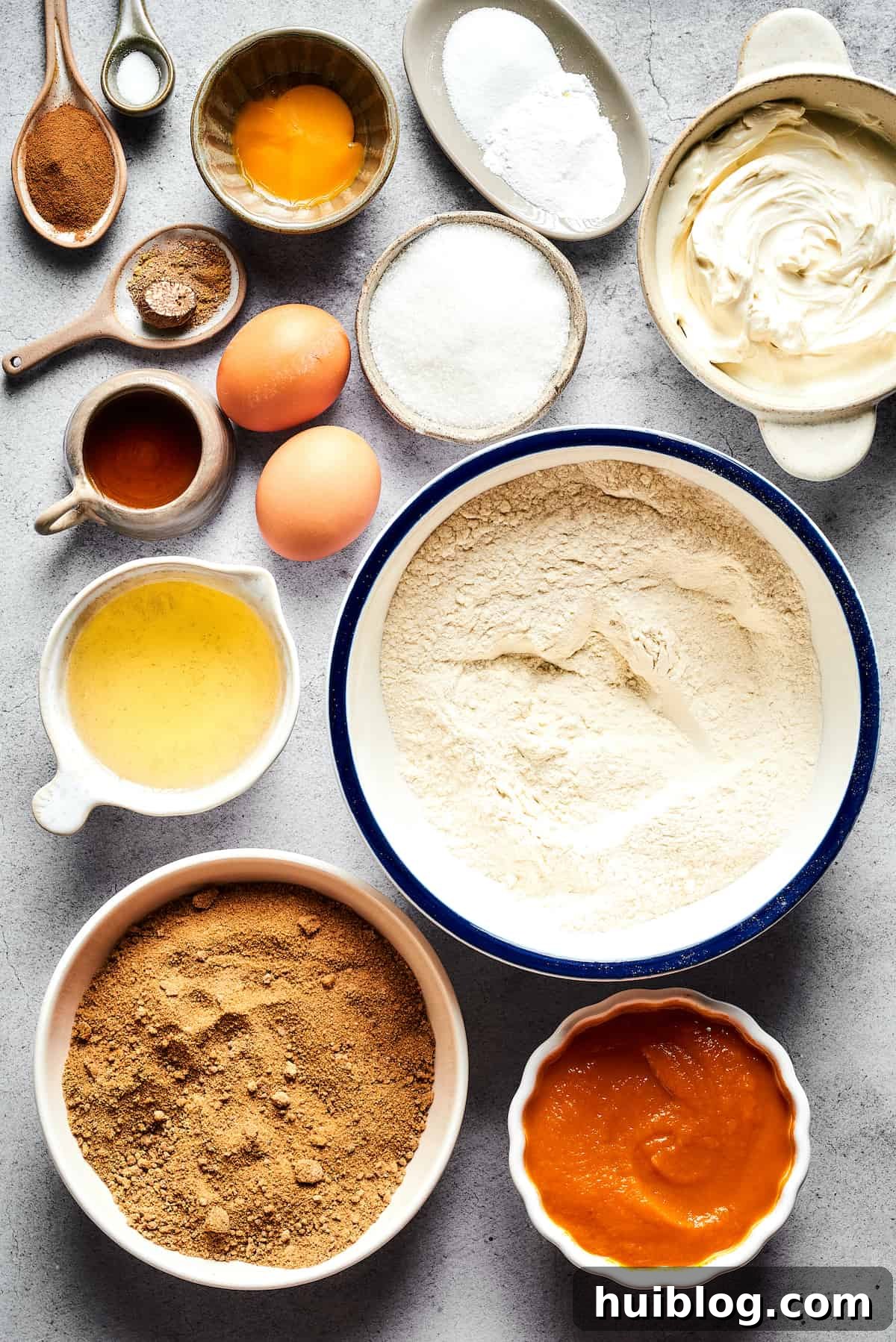 Pumpkin Cream Cheese Muffins are a heavenly mix of spiced pumpkin cake and smooth cream cheese swirl, with a buttery, streusel-like topping. A collection of key ingredients for pumpkin cream cheese muffins, arranged from top to bottom: ground cinnamon, salt, eggs and an egg yolk, baking powder and baking soda, softened cream cheese, granulated white sugar, vegetable oil, all-purpose flour, light brown sugar, and a can of pumpkin puree.