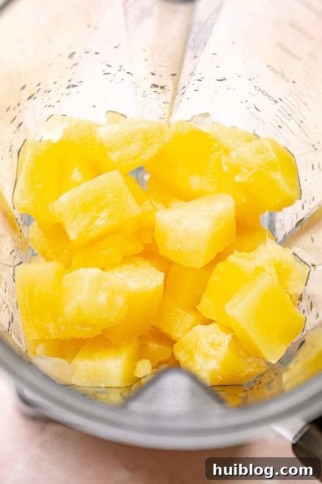 Close-up of fresh pineapple chunks and ice cubes, ready to be blended into a frosty frozen pineapple margarita.