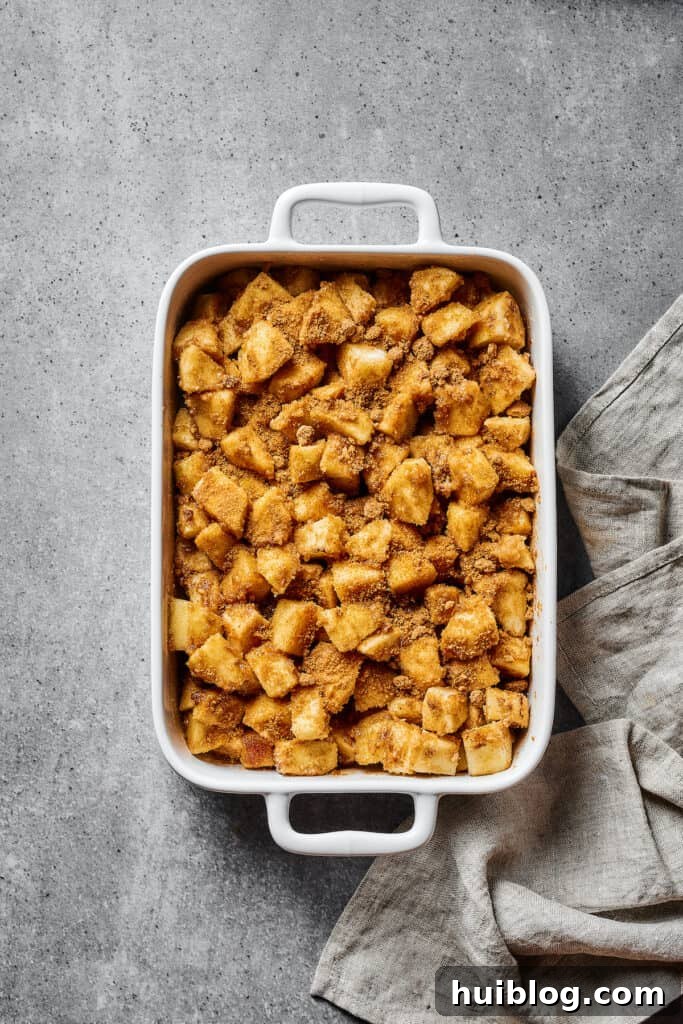 Apples coated in a spiced flour mixture, in a large baking dish.