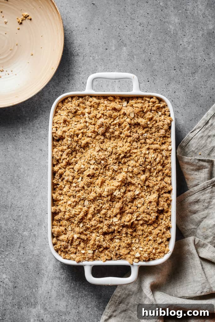 An unbaked apple crisp in a white casserole dish.