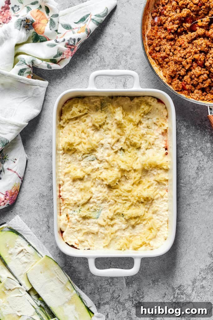 Mozzarella sprinkled over other lasagna layers in a baking dish.