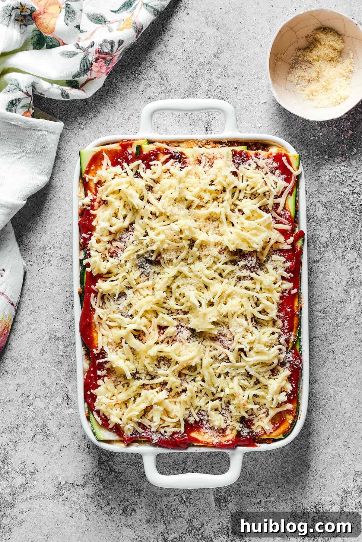 Mozzarella sprinkled on top of an unbaked lasagna.