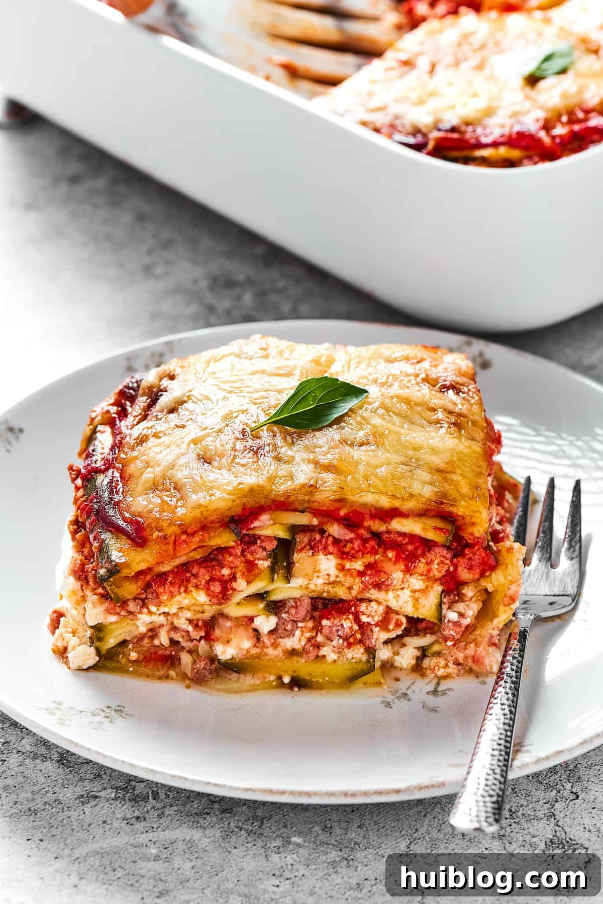 A square of zucchini lasagna on a white plate.