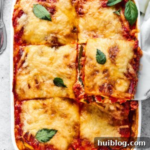 zucchini lasagna being lifted out of a white rectangular baking dish.