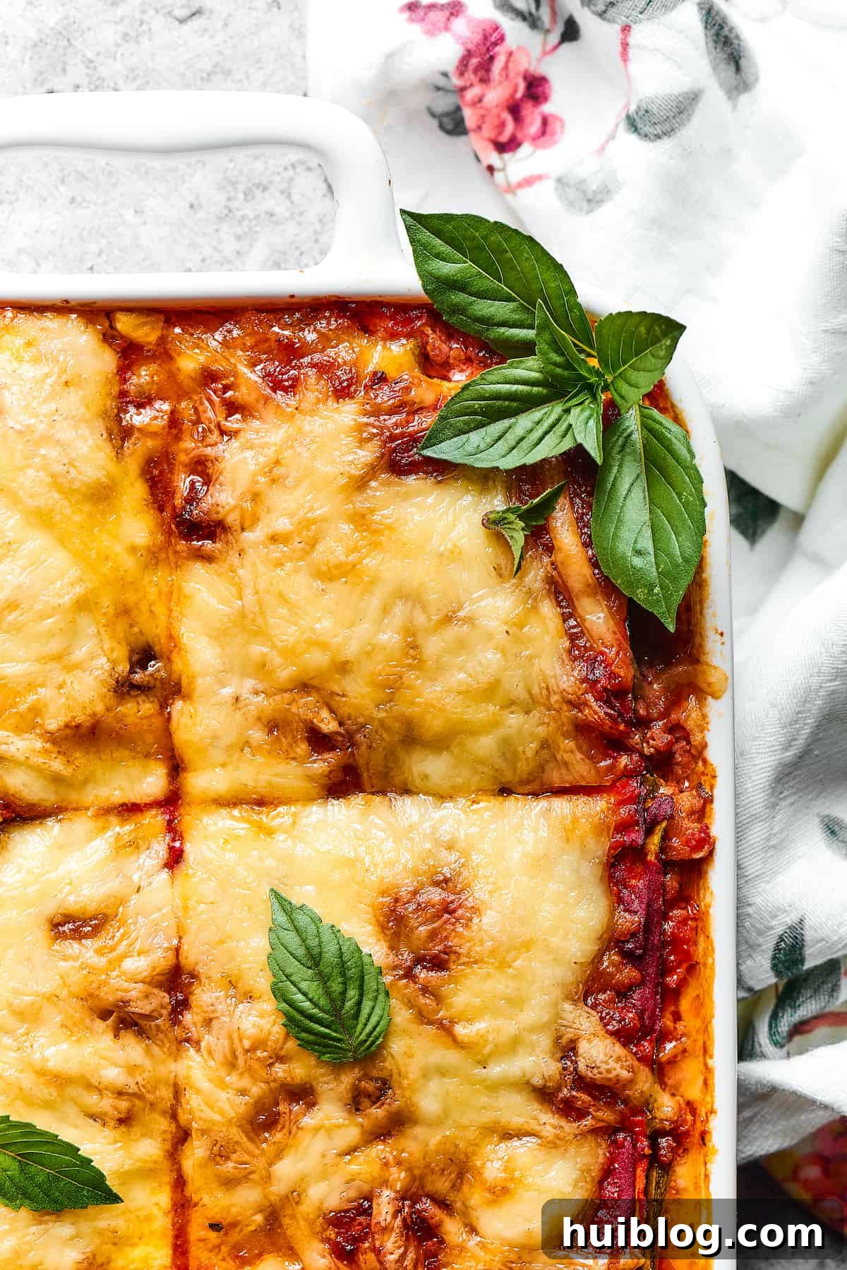 Close-up shot of a corner of zucchini lasagna, garnished with fresh basil.