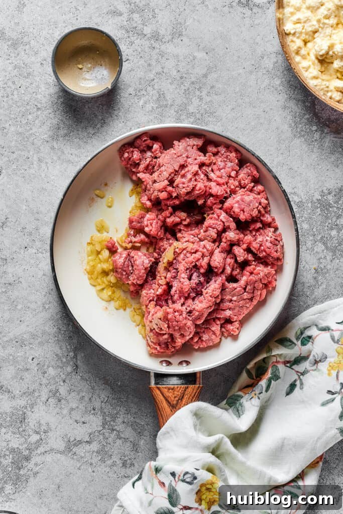 Garlic, onions, and ground beef cooking in a skillet.