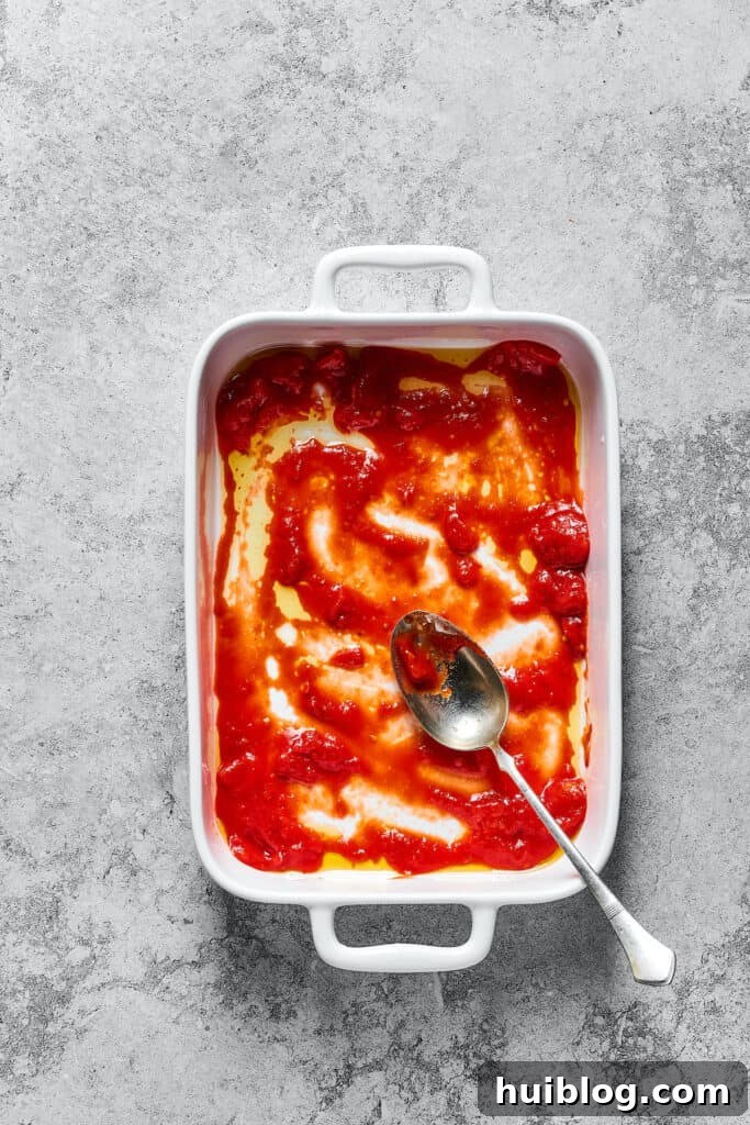 Tomato sauce in the bottom of a baking dish.