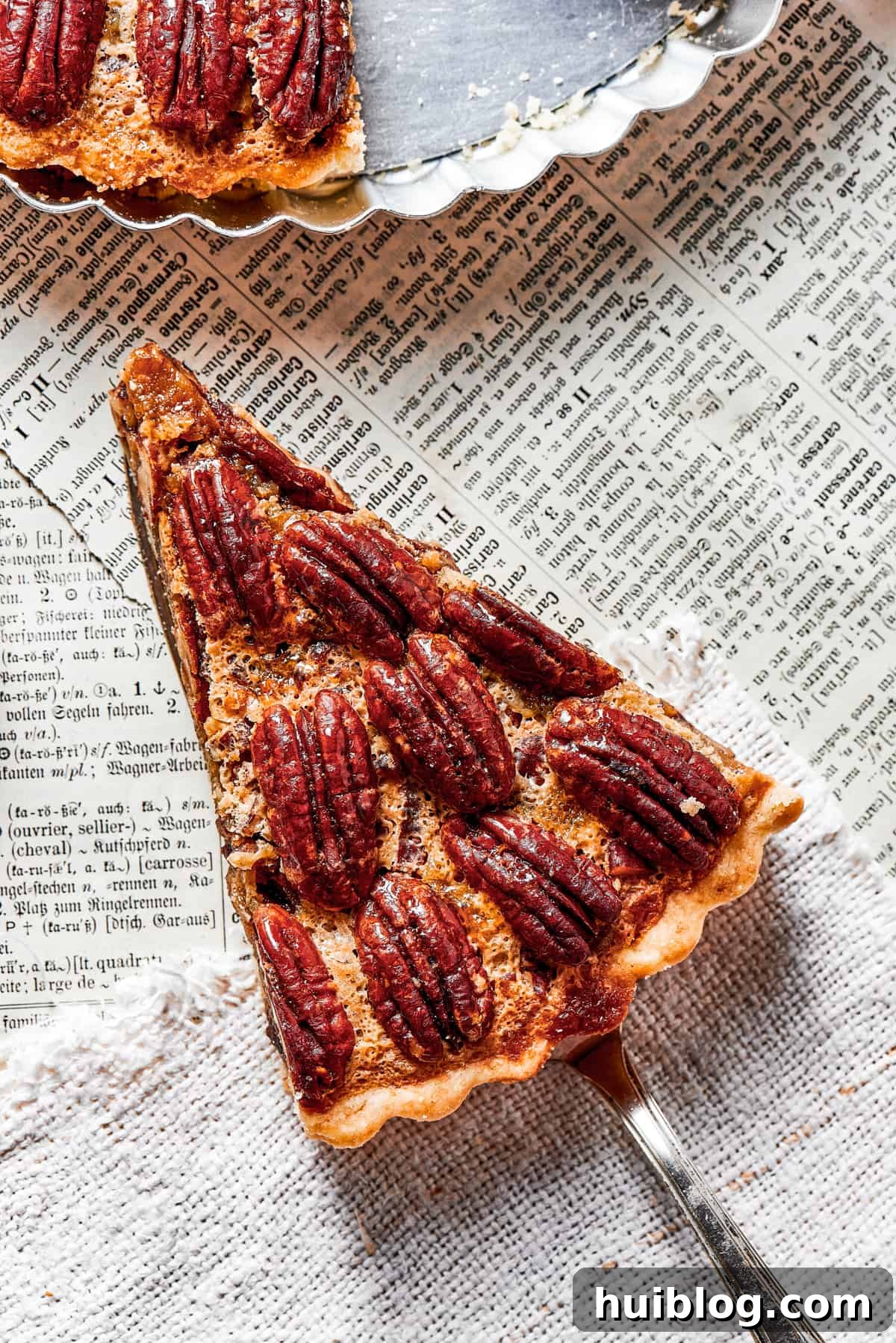 overhead shot of a slice of pie held over a newspaper, and a pie plate placed above it.