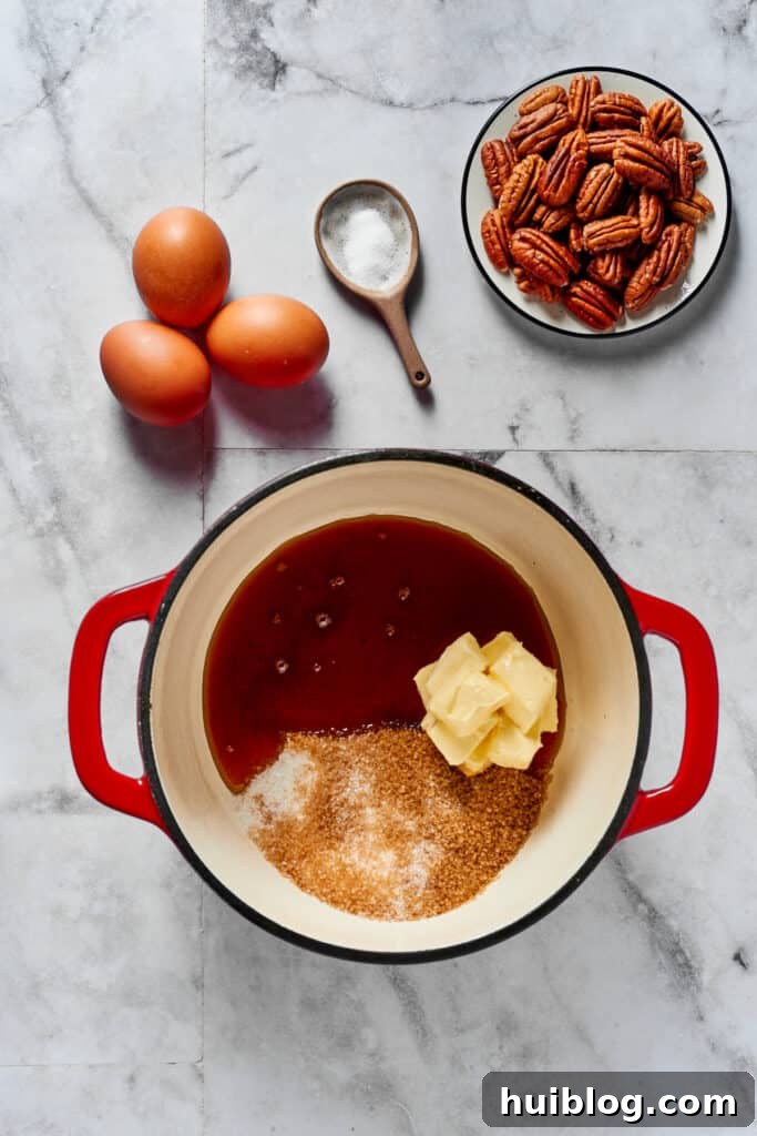 A heavy pot with butter, sugar, and syrup inside. Eggs, salt, an pecans are arranged in dishes on the work surface.