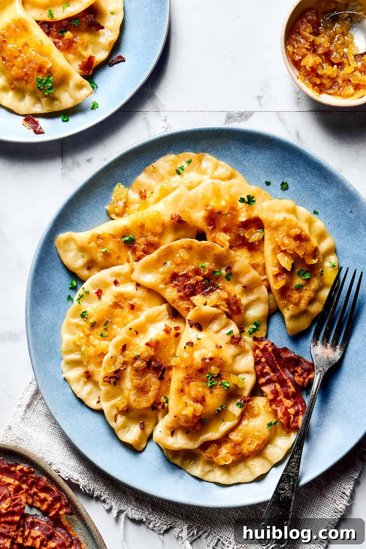 Topped with caramelized onion and crispy bacon, this easy Homemade Pierogi Recipe features a traditional cheese and potato filling. Yum! Cooked pierogi topped with bacon and onions.
