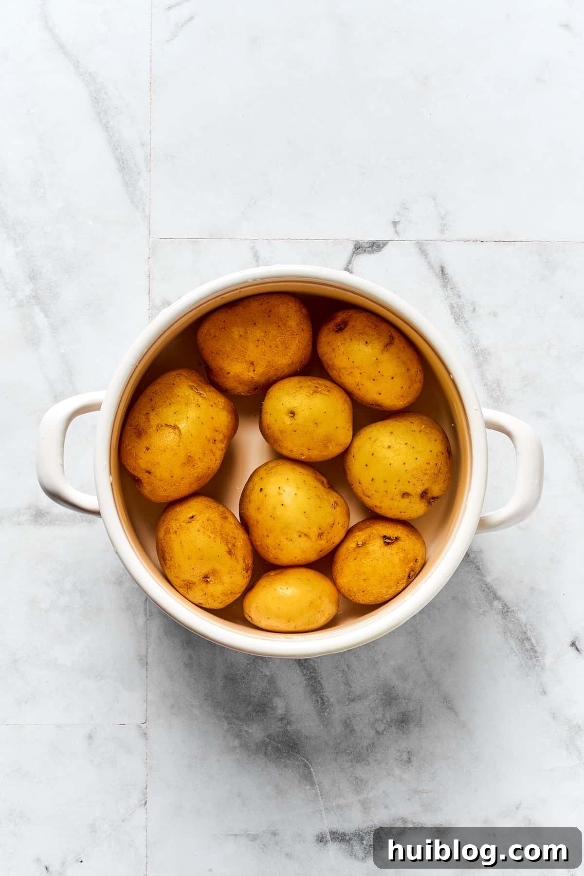 Topped with caramelized onion and crispy bacon, this easy Homemade Pierogi Recipe features a traditional cheese and potato filling. Yum! Potatoes cooking in a pot.