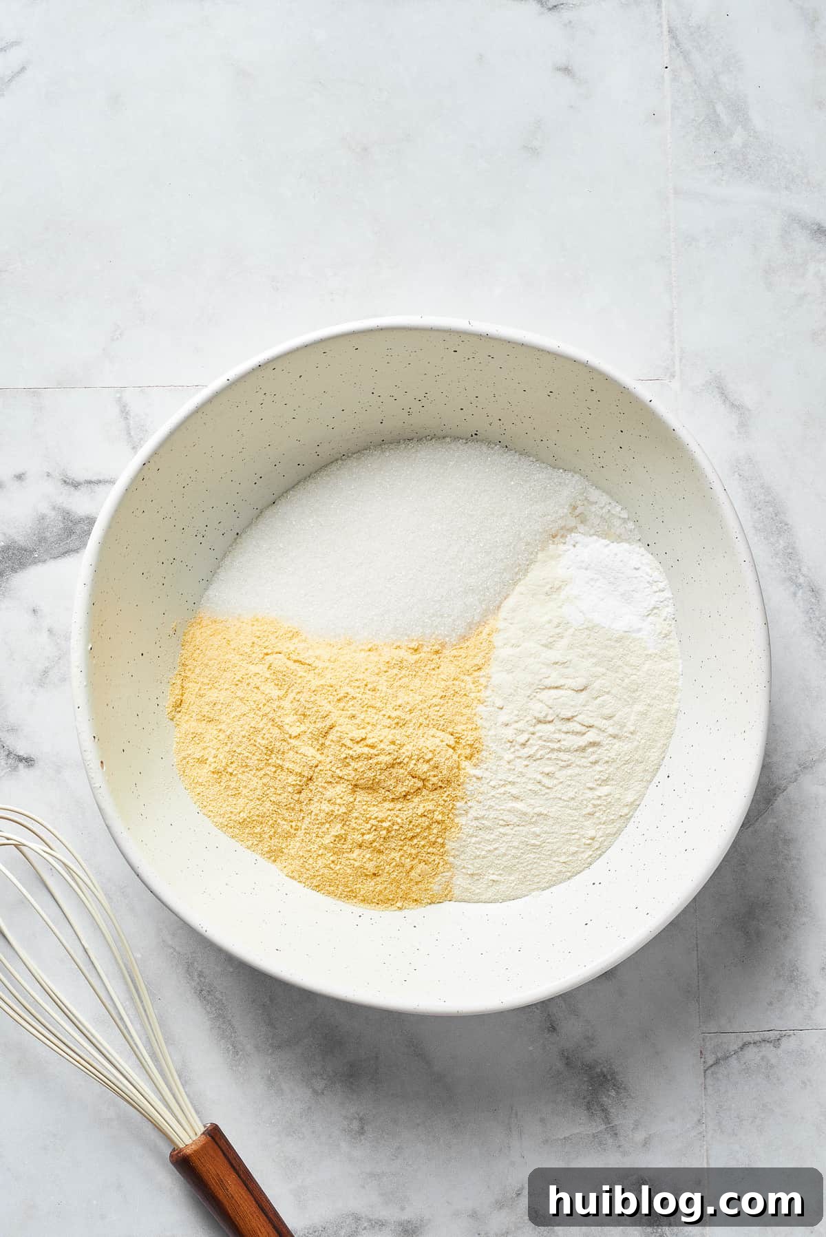 Dry cornbread ingredients, including flour, cornmeal, sugar, baking powder, and salt, are combined in a large mixing bowl.