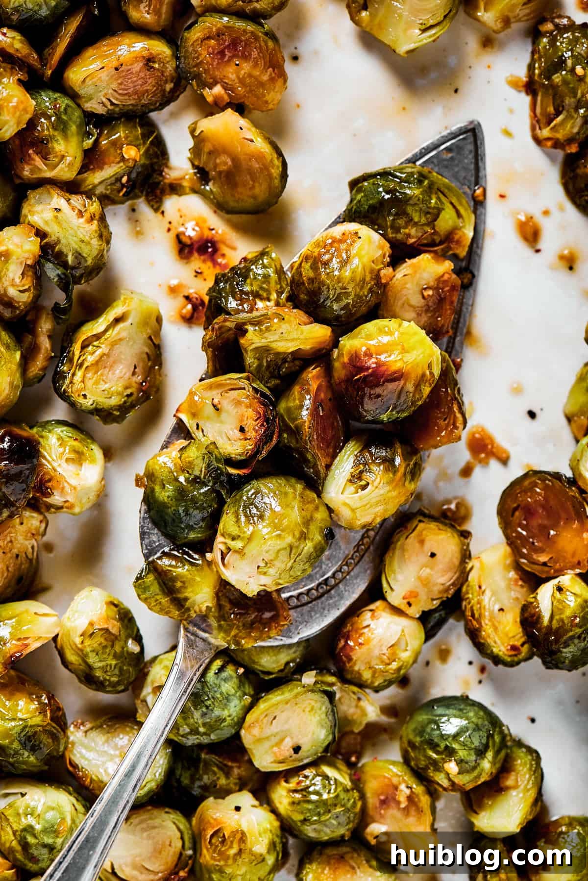 A tray of roasted brussel sprouts with a silver serving spoon, highlighting their golden brown and crispy texture, ready to be served.