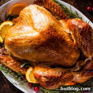 A roasted Thanksgiving turkey garnished with citrus slices and green herbs.