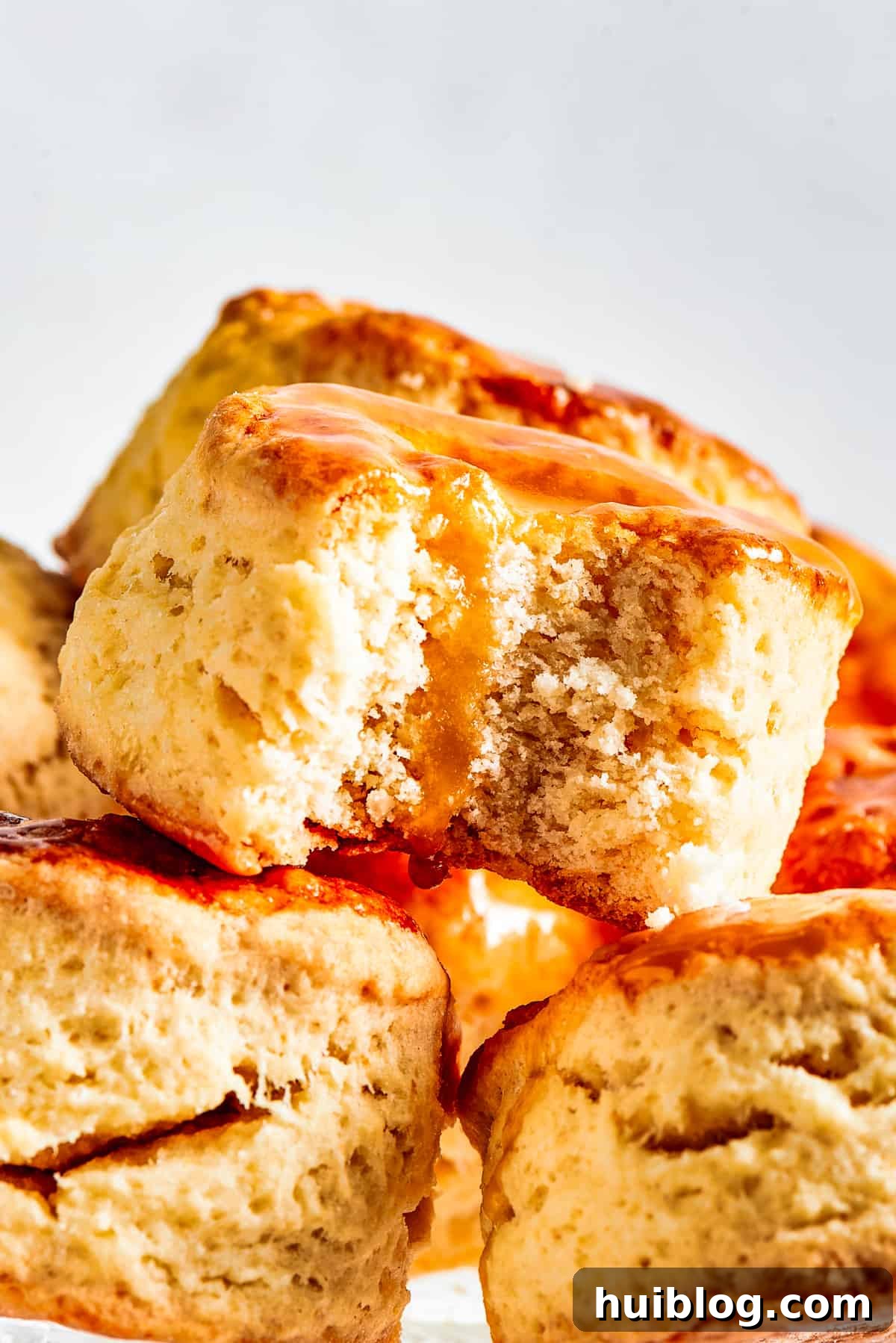 A plate featuring several homemade biscuits, with one biscuit having a bite taken out, resting on a beautifully adorned cake plate.