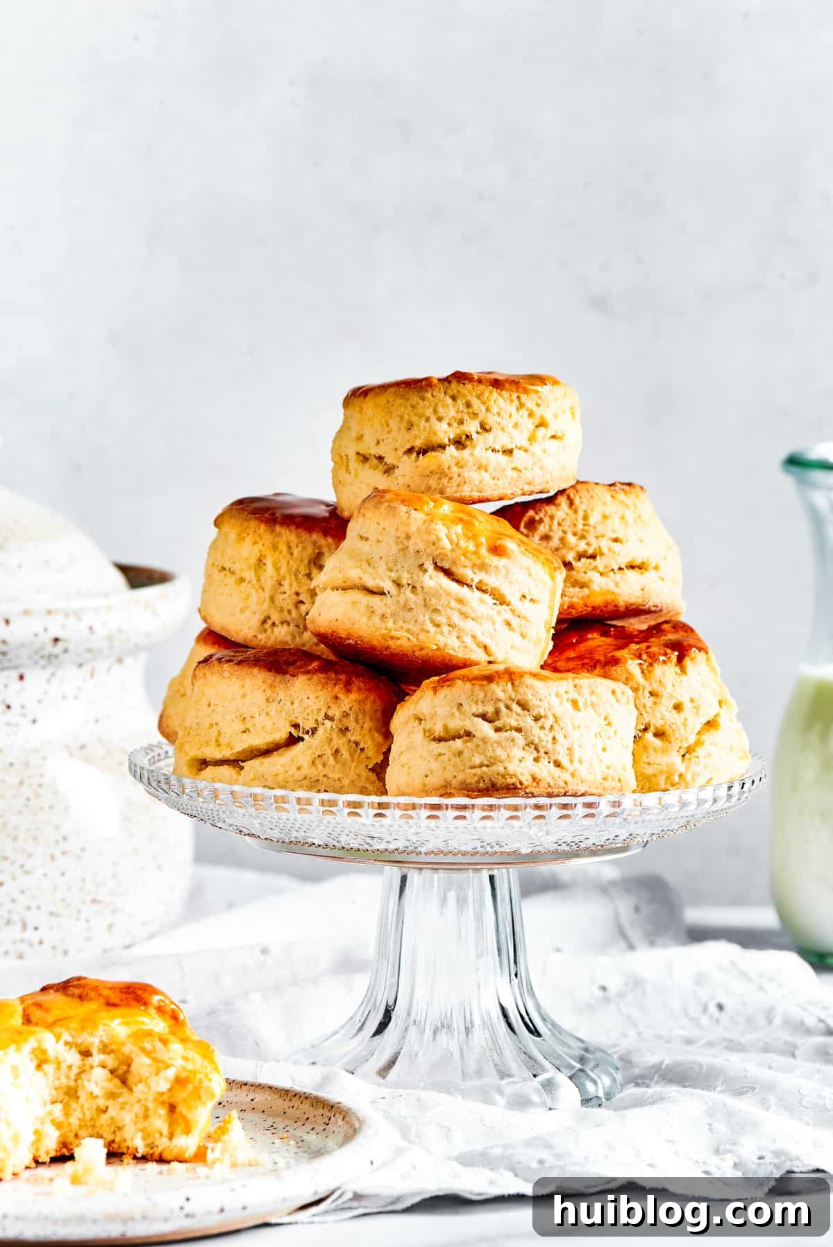 Freshly baked homemade biscuits attractively arranged on a elegant cake stand, with one biscuit delicately placed on a small saucer.