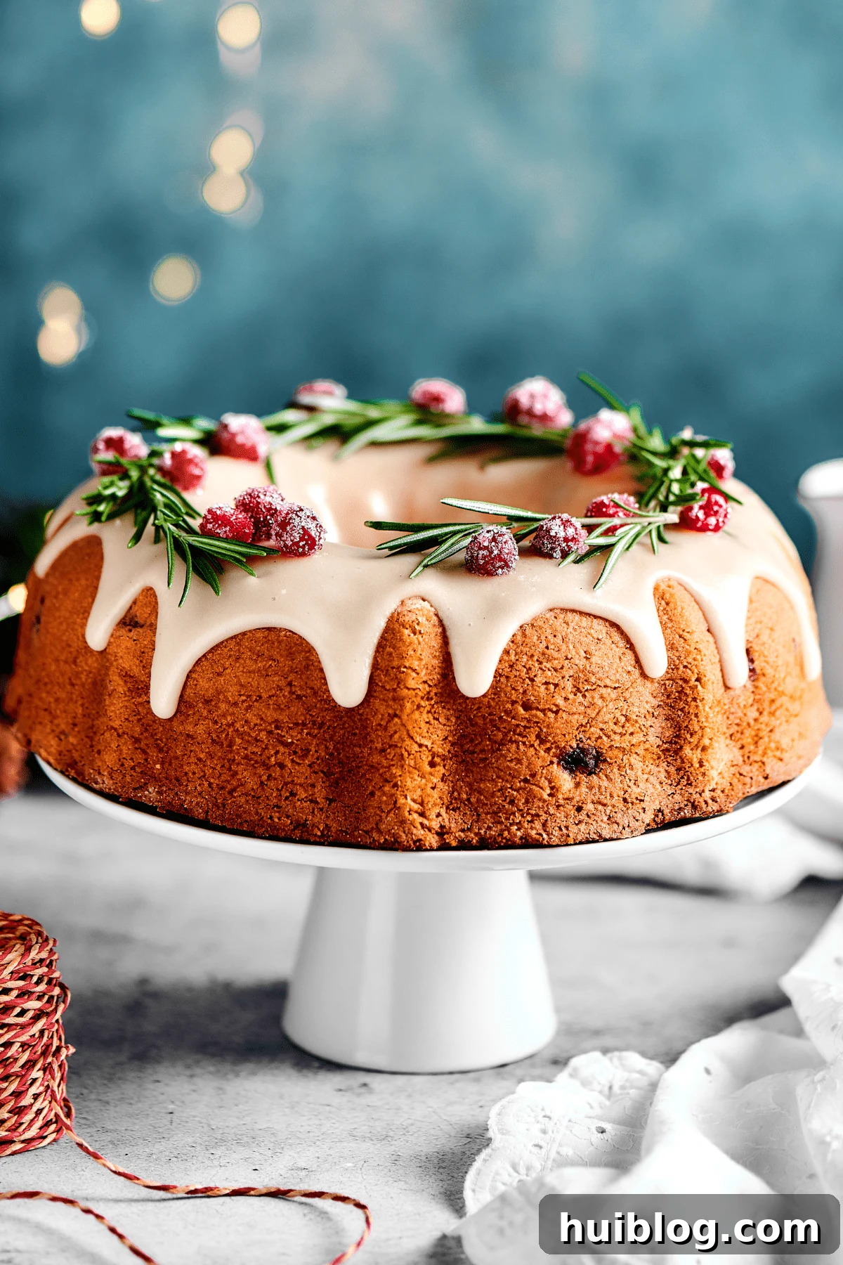 A beautifully baked Christmas Cranberry Pound Cake on a white cake stand, adorned with festive lights in the soft background.