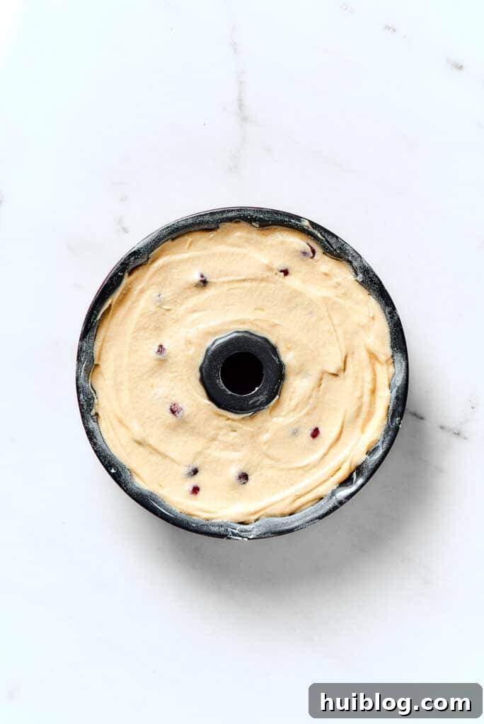 A Bundt pan filled evenly with cranberry pound cake batter, ready for baking.