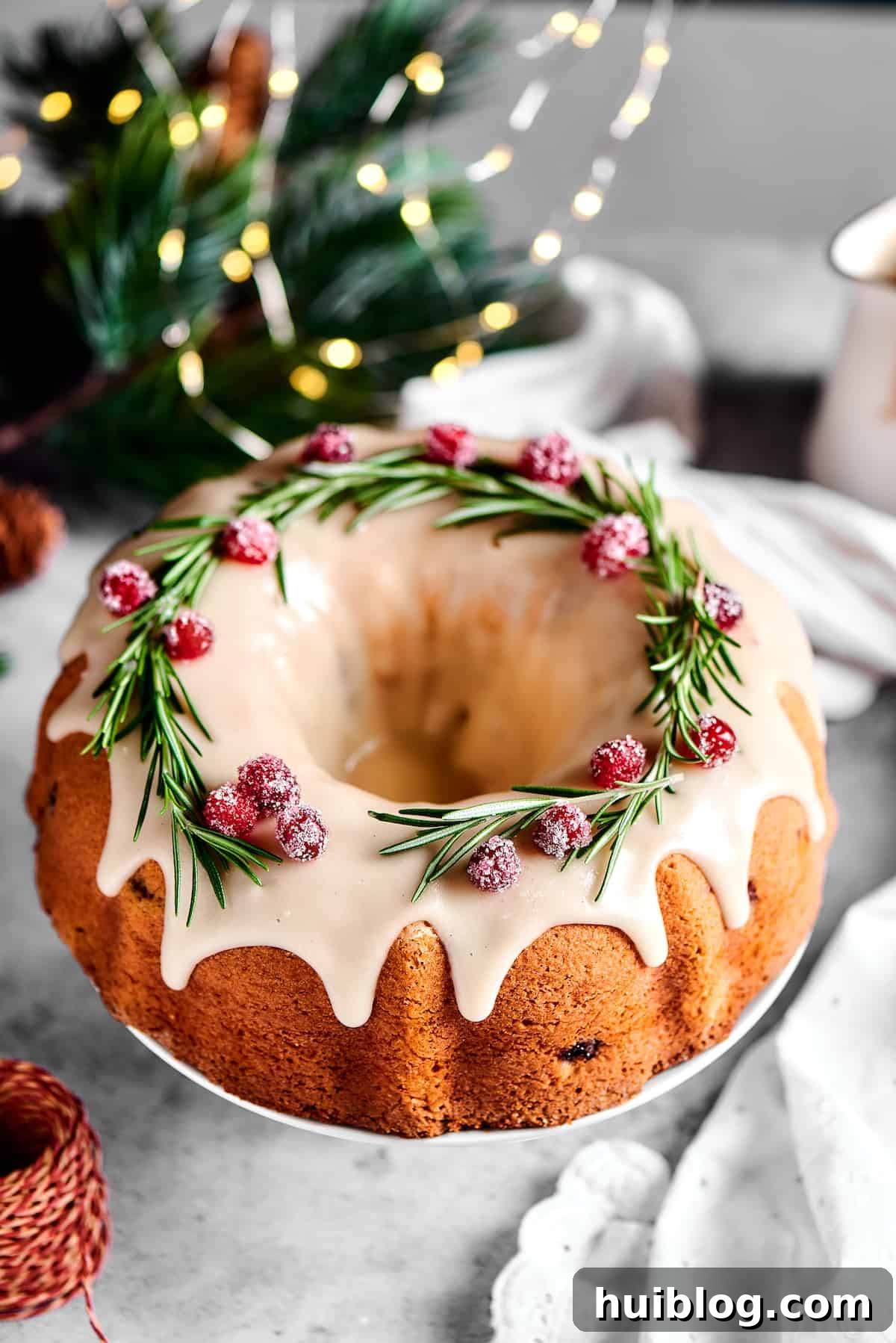An overhead shot of a festive Bundt cake, beautifully garnished with fresh rosemary sprigs and sparkling sugared cranberries.
