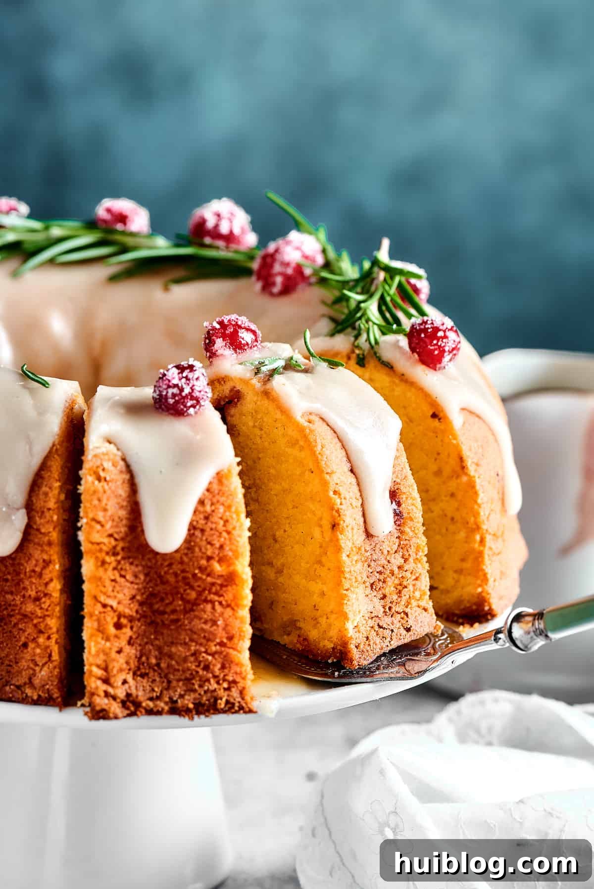 A freshly baked cranberry pound cake on a cake stand, with a few slices already cut, showcasing its beautiful interior.