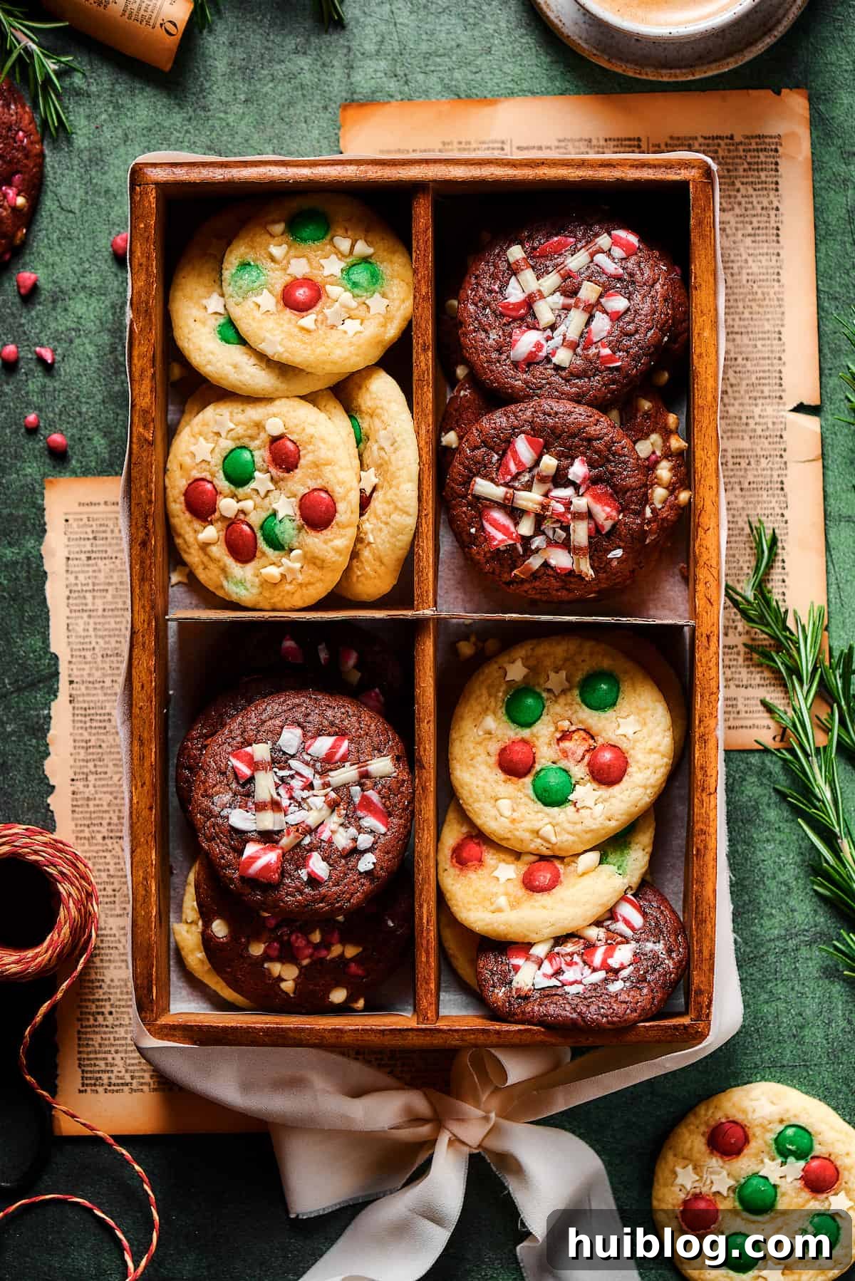 A decorative box holds an assortment of soft chocolate and vanilla Christmas cake mix cookies, vibrant with red and green M&Ms and other festive decorations, ready for holiday gifting or sharing.