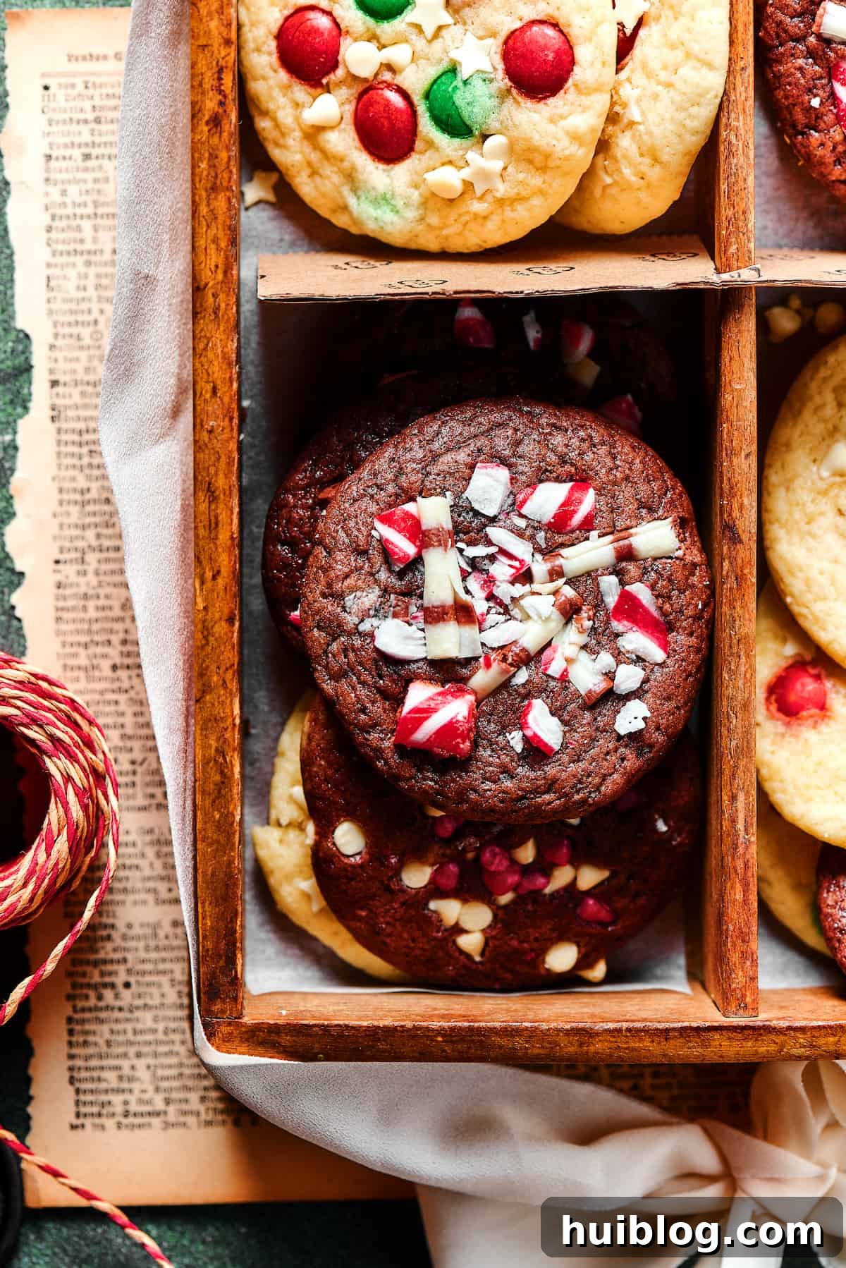 A close-up shot of a single, delectable chocolate Christmas cake mix cookie, beautifully decorated with vibrant red and green M&Ms and a scattering of crushed peppermint, resting on a white surface.