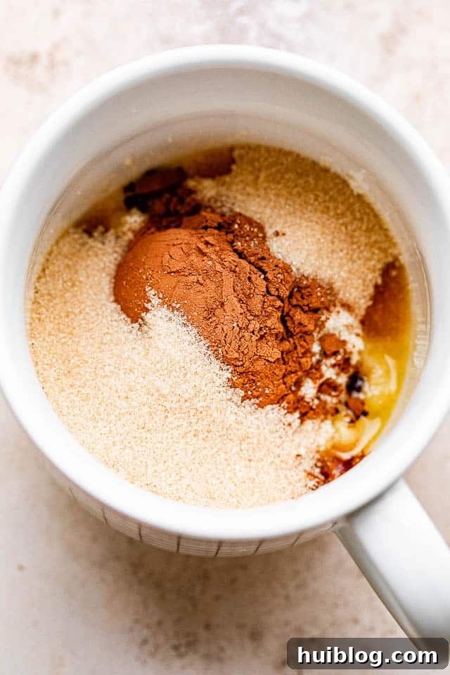 A mix of cocoa powder, flour, and sugar layered over melted butter inside a mug.