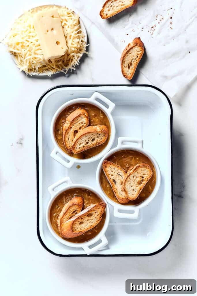 Caramelized Onion & Gruyère Soup 12 Individual oven-proof bowls of French onion soup, elegantly topped with toasted baguette slices, ready for the cheese.