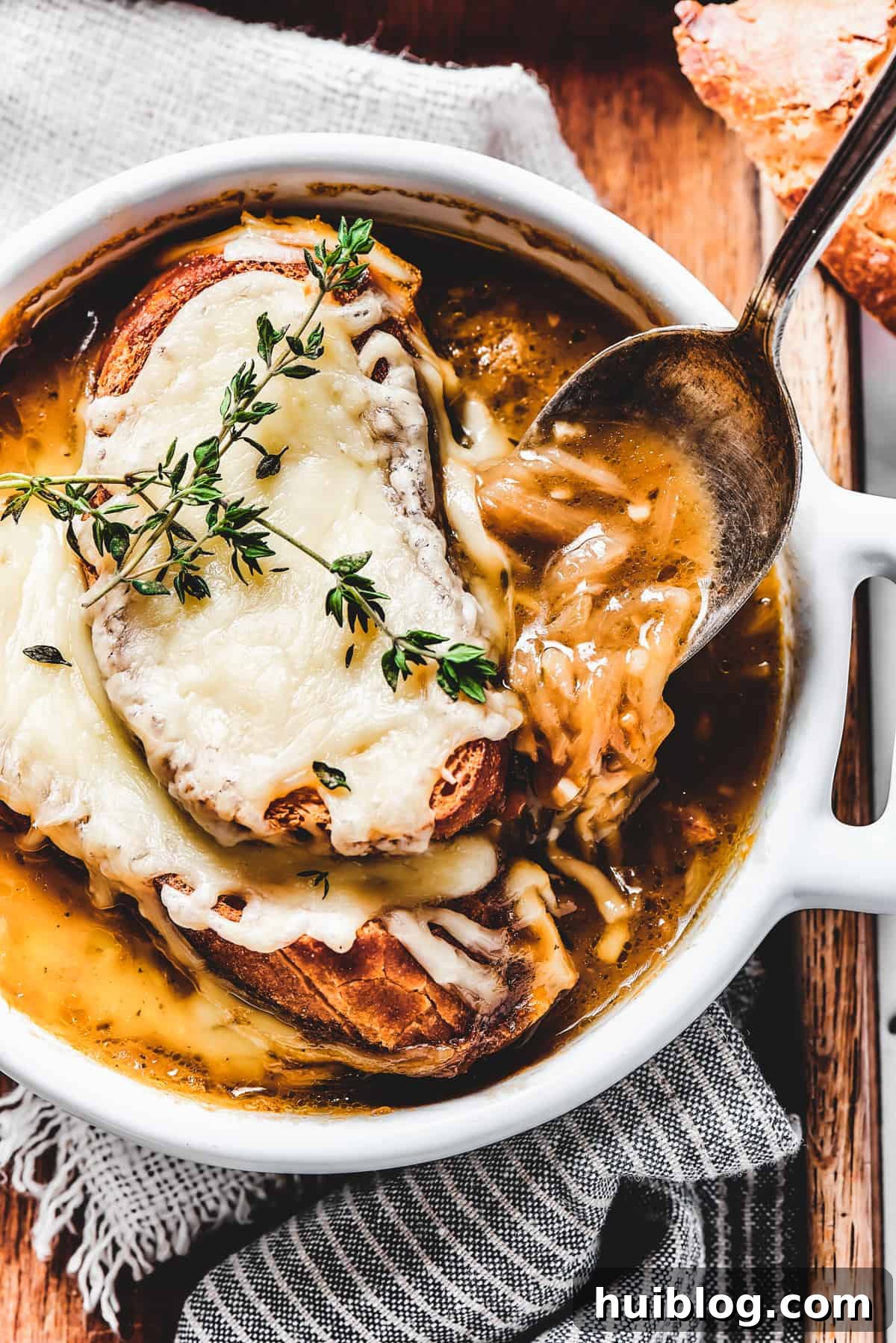 Caramelized Onion & Gruyère Soup 15 A close-up of a spoon lifting a generous portion of French onion soup, showcasing the melted cheese and tender onions.
