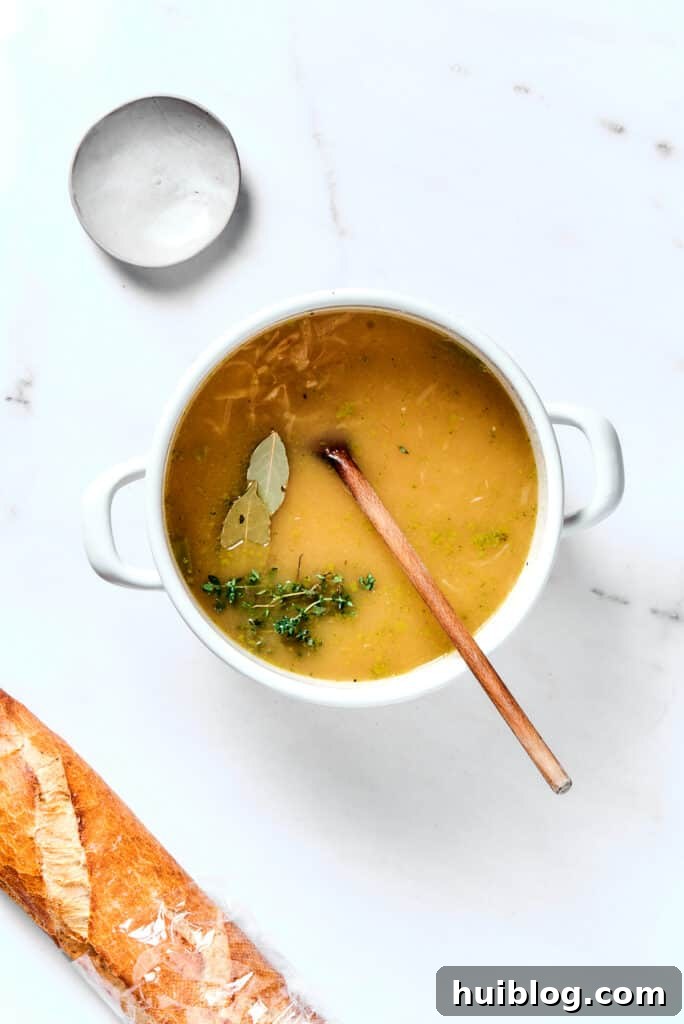 Caramelized Onion & Gruyère Soup 9 French onion soup simmering gently in a heavy pot, infused with the aroma of bay leaves and fresh thyme sprigs.