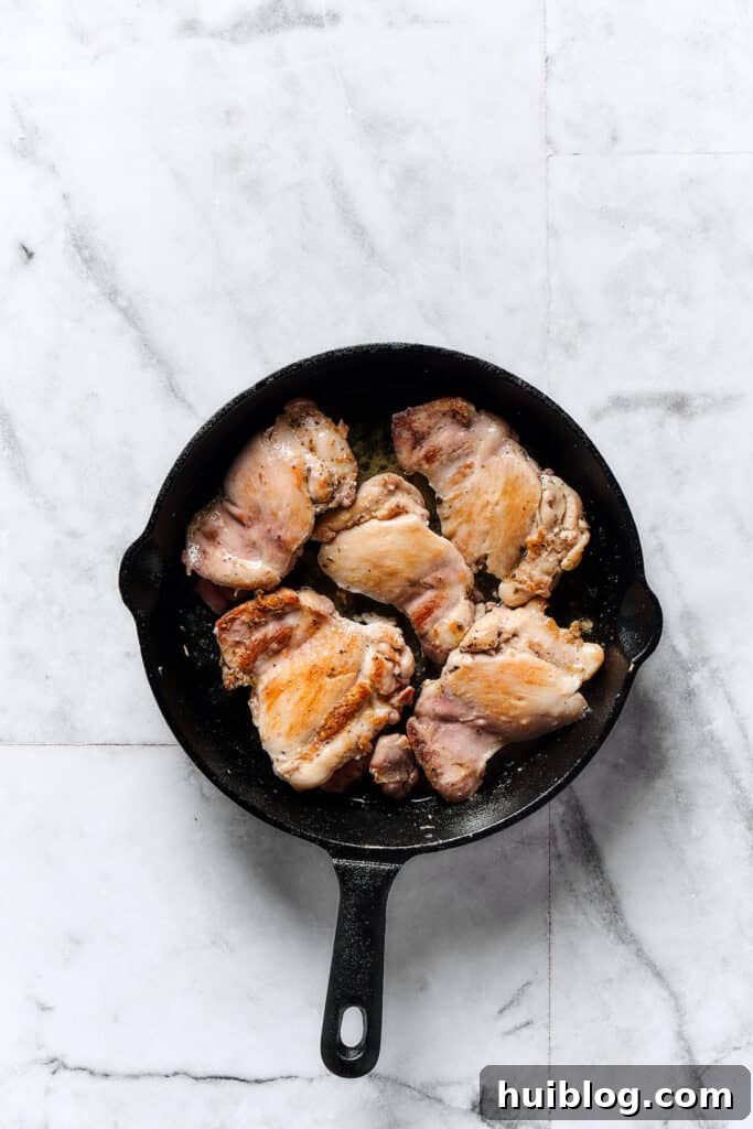 Velvety Chicken Gnocchi 2 Chicken thighs browning in a skillet, creating a delicious crust.