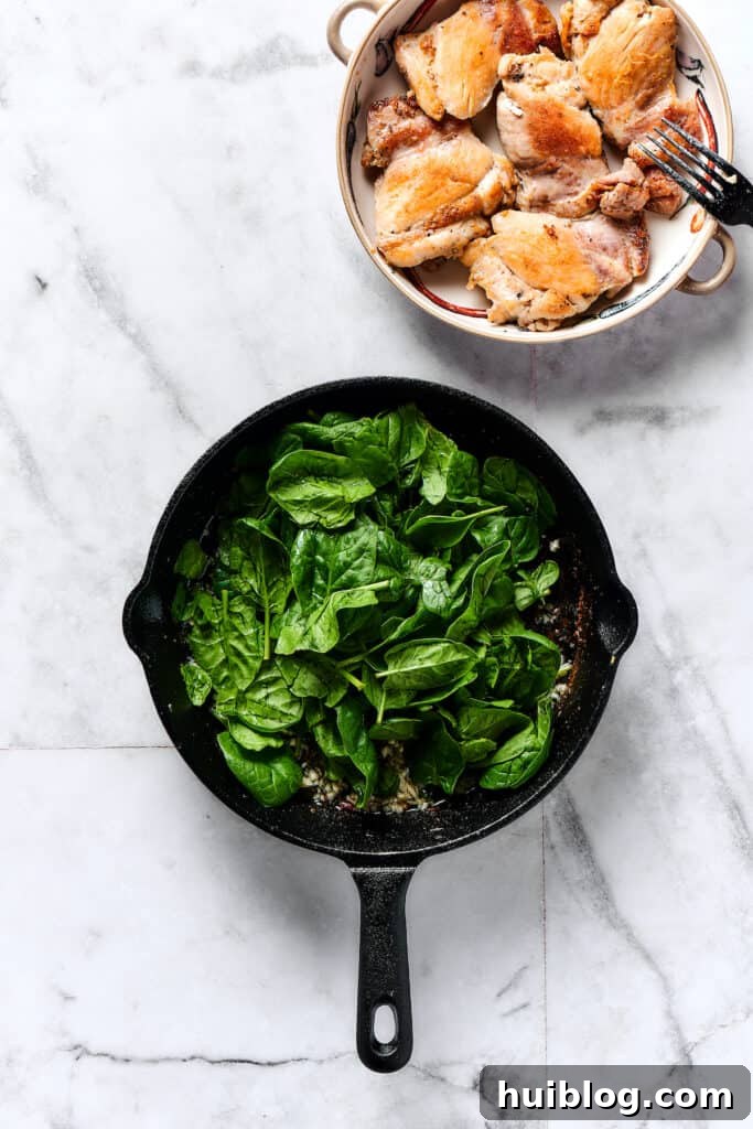 Velvety Chicken Gnocchi 3 Baby spinach wilting in a skillet with garlic and butter.