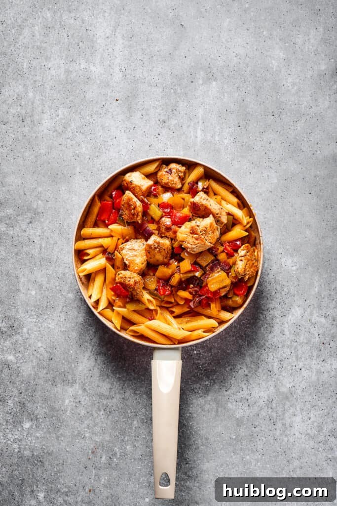 The finished Chicken Fajita Pasta dish, mixed with chicken and vegetables, ready to be served directly from the skillet.