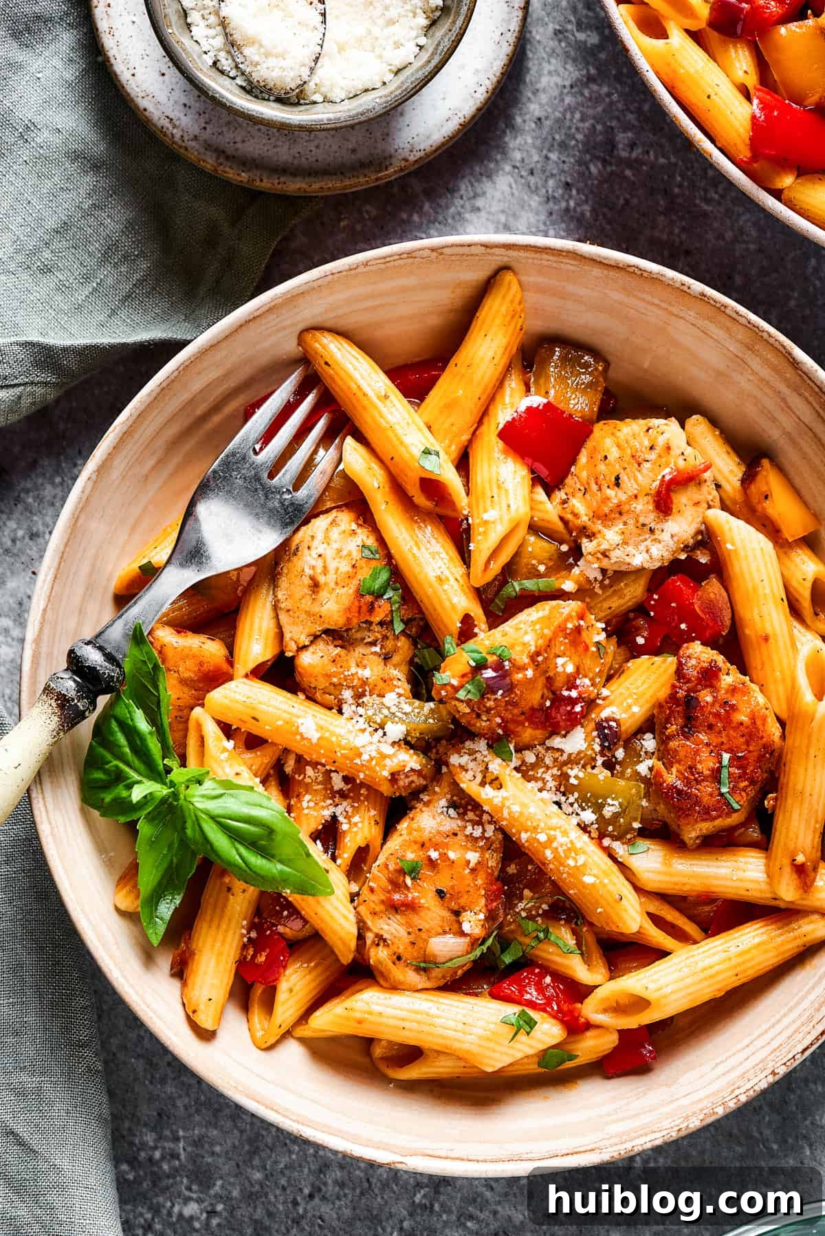 A close-up shot of a bowl filled with Chicken Fajita Pasta, showcasing the rich sauce, tender chicken, and colorful vegetables, with a fork poised to take a bite.