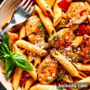 overhead close up of chicken and penne with tomatoes, peppers, and onions.