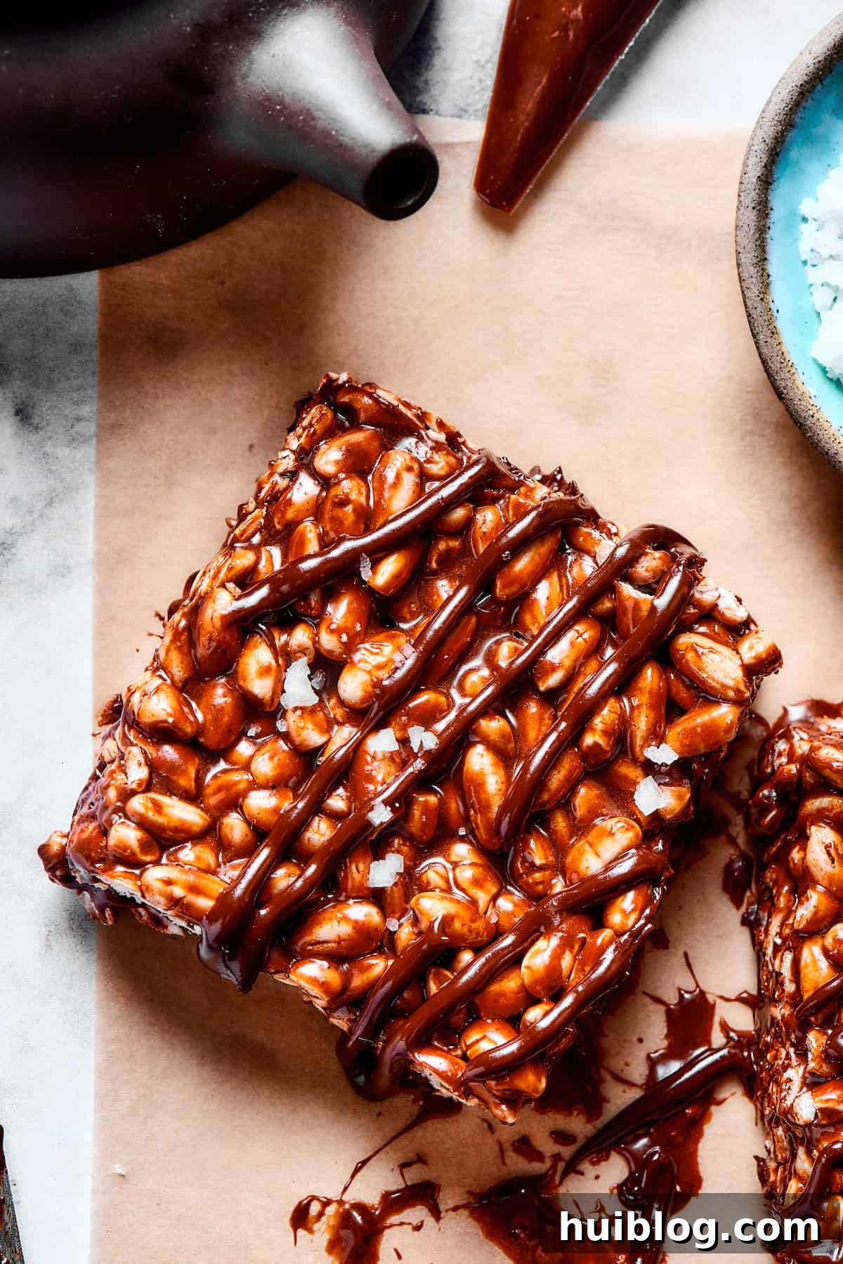A tempting close-up of a single chocolate rice krispie treat, highlighting its rich layers and appealing texture. A single, perfectly formed chocolate rice and marshmallow square with a delicate chocolate drizzle, ready to be picked up.
