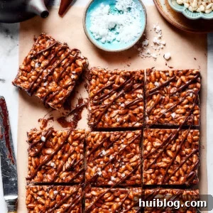 No-Bake Chocolate Crispy Treats 10 Squares of chocolate rice krispie treats next to a bowl of flaky sea salt.