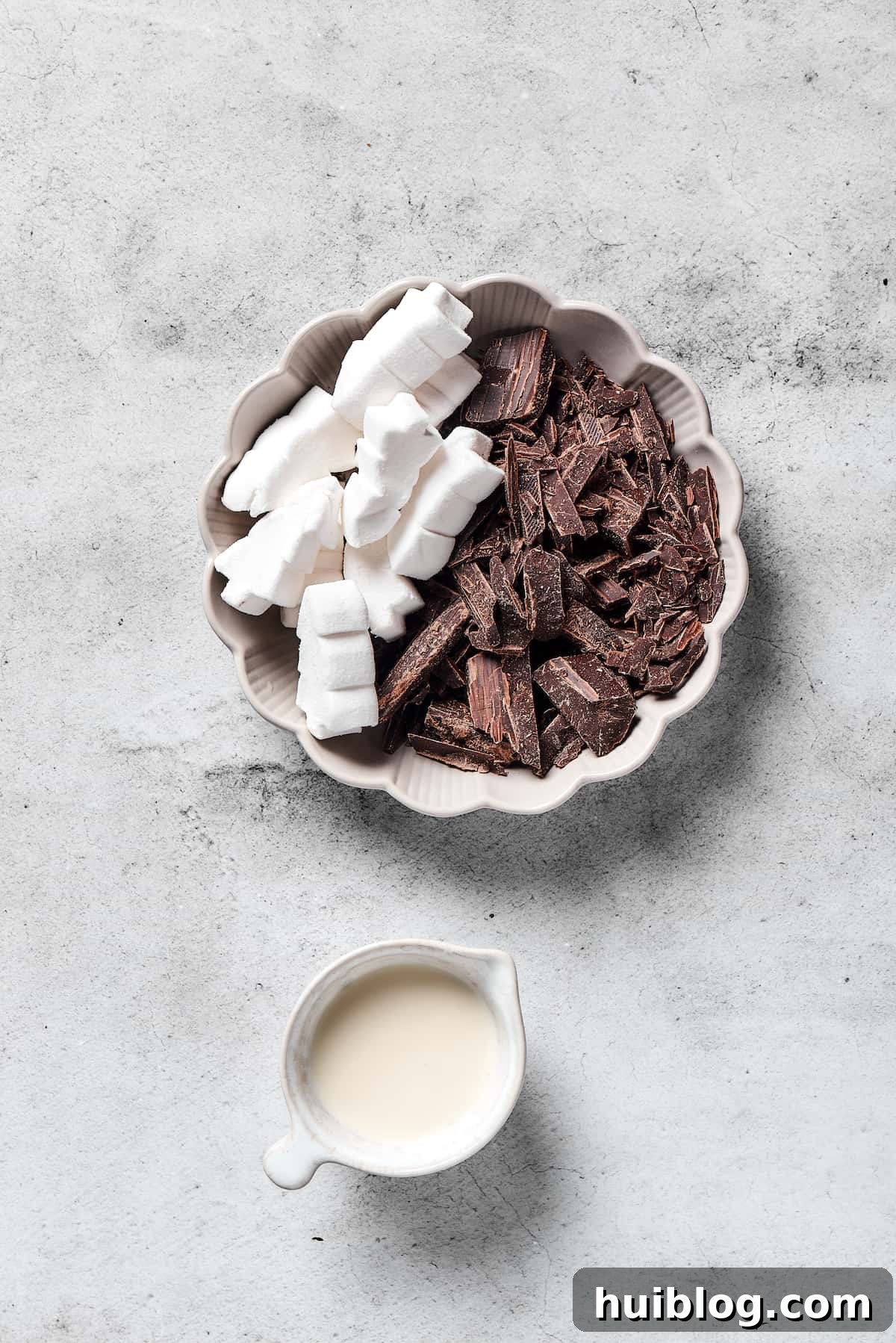 Essential components for crafting the rich and creamy topping for your chocolate rice krispie treats. Ingredients for the topping: dark chocolate, marshmallows, and heavy cream, glistening and ready for melting.