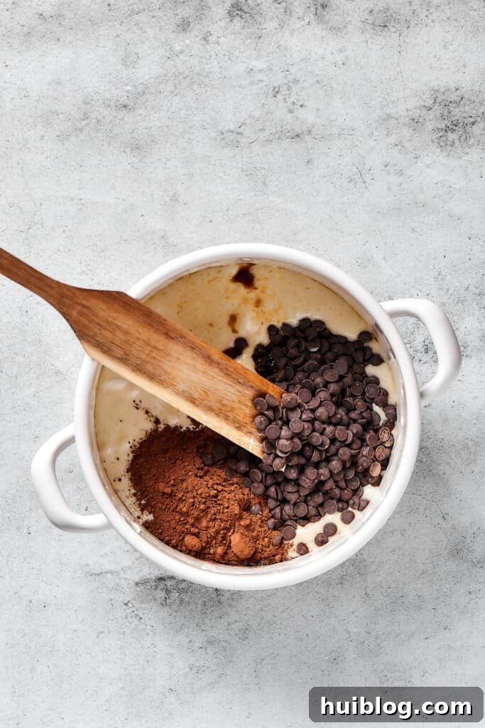 No-Bake Chocolate Crispy Treats 4 A spoon mixing dark chocolate chips and cocoa powder into a warm, melted butter and marshmallow mixture.