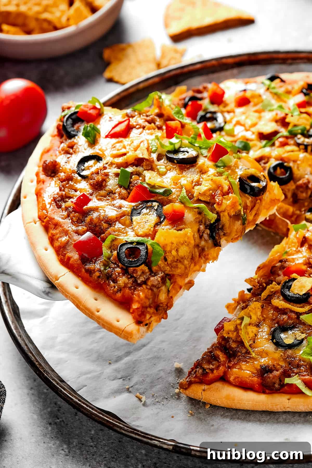 Easy Taco Pizza: A Fun and Customizable Dinner Idea Lifting a slice of Southwestern pizza with a pie server, showcasing vibrant toppings and melted cheese.
