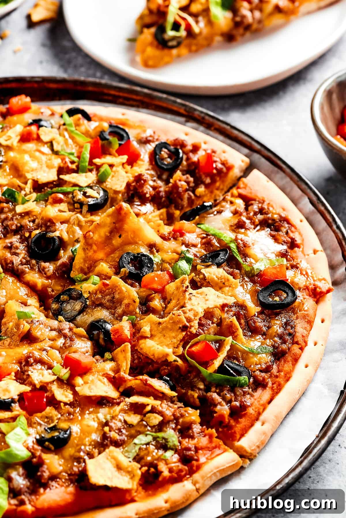 A vibrant homemade Mexican pizza adorned with fresh shredded lettuce, perfectly crushed tortilla chips, and an array of savory toppings.
