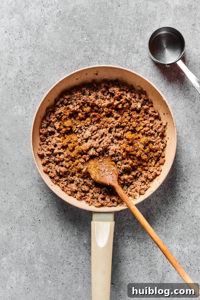 Fiesta Pie 3 Seasoned taco meat cooked to perfection in a skillet, ready for pizza assembly.