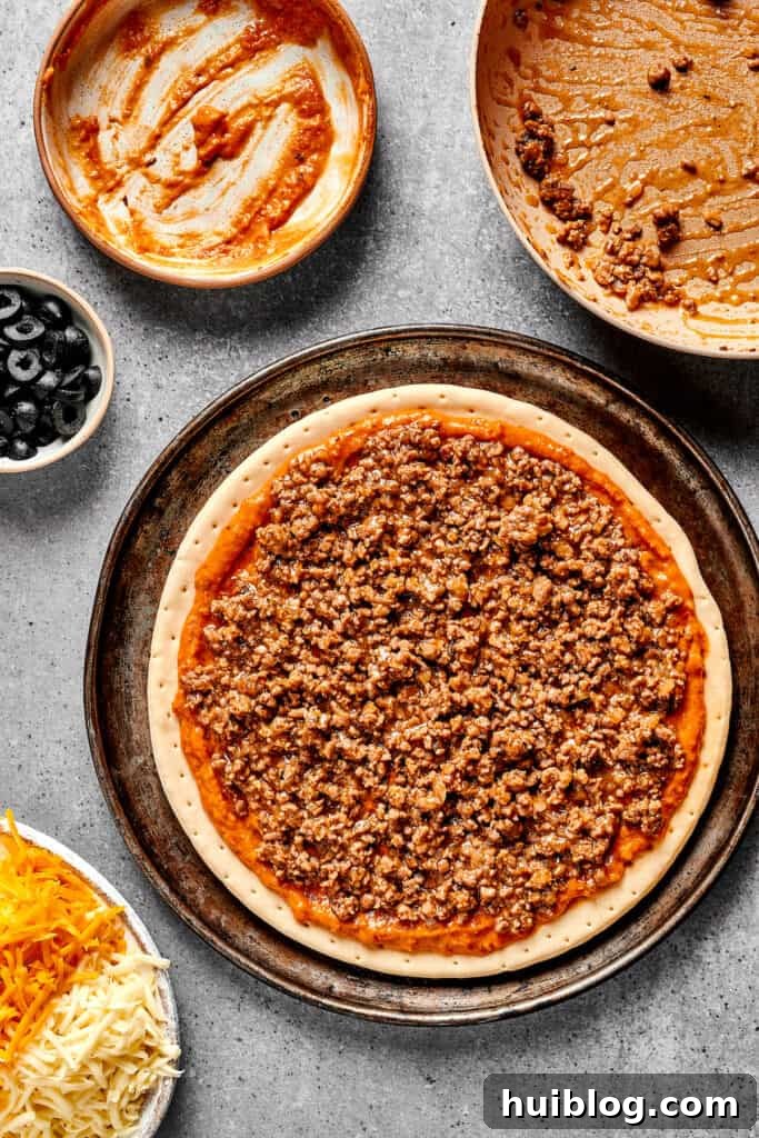 Fiesta Pie 5 A pizza crust artfully layered with the refried bean sauce, seasoned ground beef, and an initial layer of cheese.