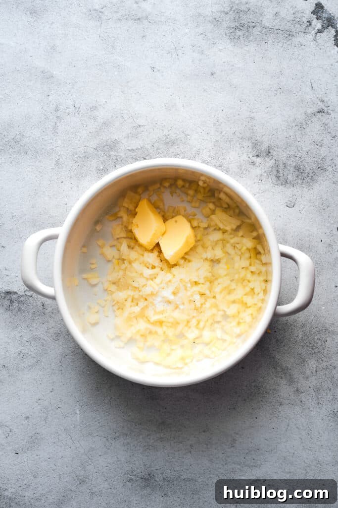 Chopped onions and butter sizzling gently in a large soup pot, forming the aromatic base for the soup.