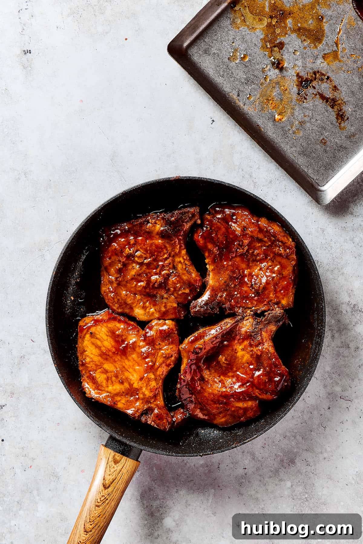 Gorgeous Brown Sugar Pork Chops may look fancy, but they are actually so simple to make! Savory, pan-fried chops with brown sugar glaze. Chef's hand carefully glazing pork chops in the rich brown sugar sauce within a hot skillet.